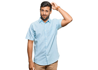 Fototapeta premium Handsome hispanic man wearing casual clothes confuse and wonder about question. uncertain with doubt, thinking with hand on head. pensive concept.