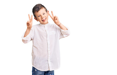 Cute blond kid wearing elegant shirt smiling with tongue out showing fingers of both hands doing victory sign. number two.