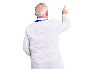 Senior handsome grey-haired man wearing doctor coat and stethoscope posing backwards pointing ahead...