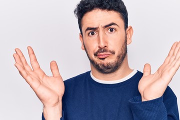 Naklejka premium Young hispanic man wearing casual clothes clueless and confused with open arms, no idea and doubtful face.