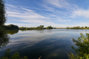 Beautiful summer landscape with lake and serene blue sky reflected in the water surface. Calm morning scenery