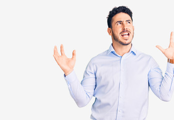 Young hispanic man wearing business clothes crazy and mad shouting and yelling with aggressive expression and arms raised. frustration concept.