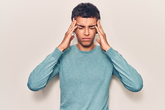 Young african amercian man wearing casual clothes with hand on head, headache because stress. suffering migraine.