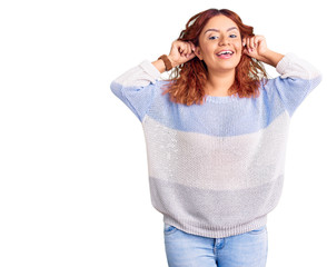 Young latin woman wearing casual clothes smiling pulling ears with fingers, funny gesture. audition...