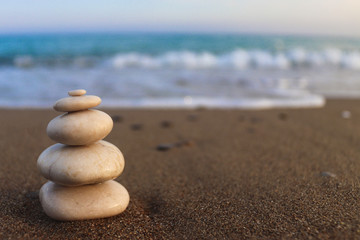 Fototapeta na wymiar Pyramid of stones on the seashore. Zen concept. Concept of harmony, stability, life balance, relaxation and meditation. Blurred background, copy space for text, selective focus