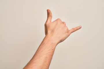 Hand of caucasian young man showing fingers over isolated white background gesturing Hawaiian shaka greeting gesture, telephone and communication symbol