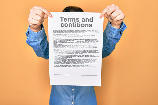 Woman holding terms and conditions document paper standing over isolated yellow background