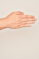 Hand of caucasian young man showing fingers over isolated white background stretching and reaching with open hand for handshake, showing back of the hand