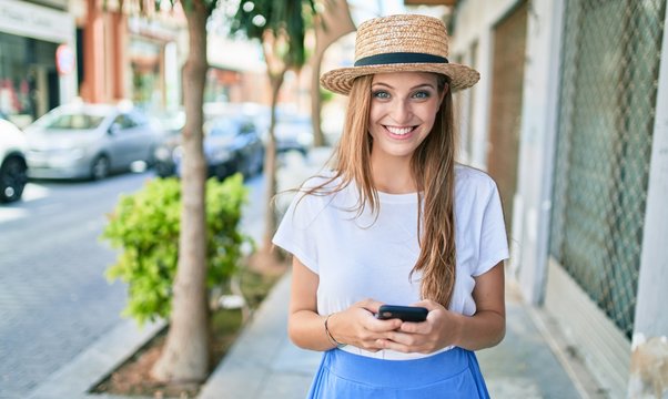 Young blonde woman on vacation smiling happy using smartphone at street of city