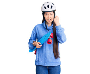 Young beautiful chinese woman wearing security helmet holding skate annoyed and frustrated shouting with anger, yelling crazy with anger and hand raised