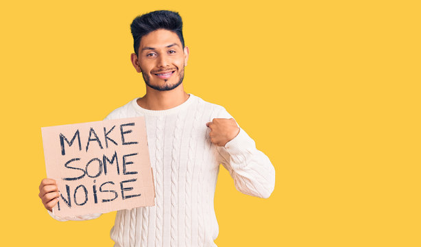 Handsome latin american young man holding make some noise banner pointing finger to one self smiling happy and proud