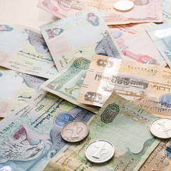Closeup of different UAE dirhams currency notes and coins , paper money on a light wooden table from high angle