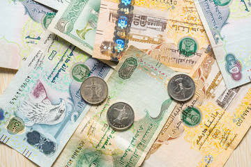 Fototapeta na wymiar Closeup of different UAE dirhams currency notes and coins , paper money on a light wooden table from high angle