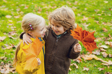 Adorable happy kids outdoors on autumn day, little boy kissing a girl. Funny little couple.