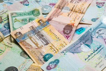 Closeup of different UAE dirhams currency notes and coins , paper money on a light wooden table from high angle