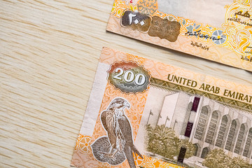 Closeup of UAE 200 dirhams currency notes on light wooden table from high angle, paper money