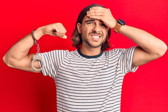 Young handsome man wearing prisoner handcuffs stressed and frustrated with hand on head, surprised and angry face