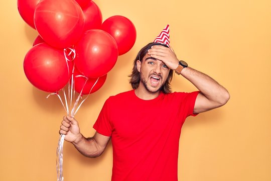 Young handsome man holding balloons stressed and frustrated with hand on head, surprised and angry face