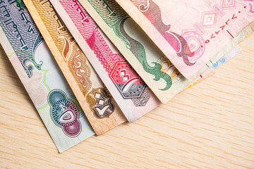 Closeup of different UAE dirhams currency notes, paper money on a light wooden table from high angle