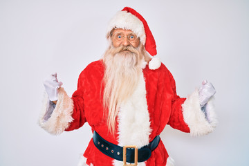 Old senior man with grey hair and long beard wearing santa claus costume with suspenders very happy and excited doing winner gesture with arms raised, smiling and screaming for success. celebration.