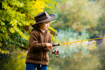 Kids fishing by mountain lake in autumn.