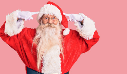 Old senior man with grey hair and long beard wearing traditional santa claus costume smiling pointing to head with both hands finger, great idea or thought, good memory