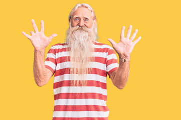 Old senior man with grey hair and long beard wearing striped tshirt showing and pointing up with fingers number ten while smiling confident and happy.