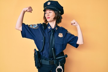 Young beautiful woman wearing police uniform showing arms muscles smiling proud. fitness concept.