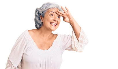 Senior woman with gray hair wearing bohemian style very happy and smiling looking far away with hand over head. searching concept.