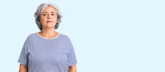 Senior woman with gray hair wearing casual striped clothes relaxed with serious expression on face....