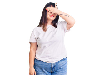 Young plus size woman wearing casual clothes smiling and laughing with hand on face covering eyes for surprise. blind concept.