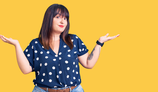 Young plus size woman wearing casual clothes clueless and confused expression with arms and hands raised. doubt concept.