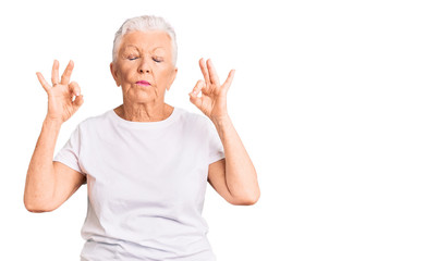 Senior beautiful woman with blue eyes and grey hair wearing casual white tshirt relaxed and smiling with eyes closed doing meditation gesture with fingers. yoga concept.