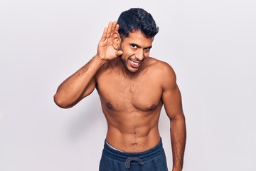 Fototapeta premium Young latin man standing shirtless smiling with hand over ear listening an hearing to rumor or gossip. deafness concept.