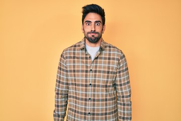Obraz premium Handsome hispanic man with beard wearing casual clothes puffing cheeks with funny face. mouth inflated with air, crazy expression.