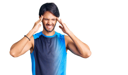 Handsome hispanic man wearing sportswear with hand on head for pain in head because stress. suffering migraine.