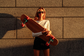 A girl in the evening city rides a longboard.