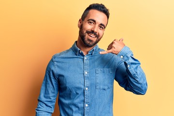 Young hispanic man wearing casual clothes smiling doing phone gesture with hand and fingers like talking on the telephone. communicating concepts.