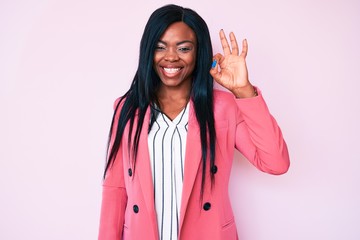 Young african american woman wearing business clothes smiling positive doing ok sign with hand and fingers. successful expression.