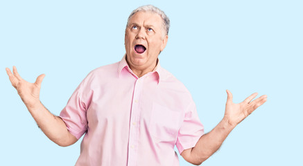 Senior grey-haired man wearing casual clothes crazy and mad shouting and yelling with aggressive expression and arms raised. frustration concept.