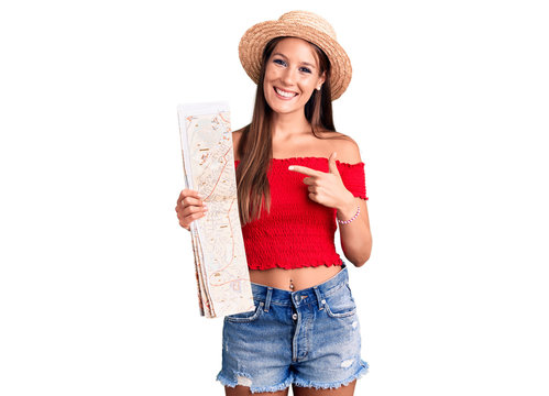 Young beautiful hispanic woman wearing summer hat holding city map smiling happy pointing with hand and finger