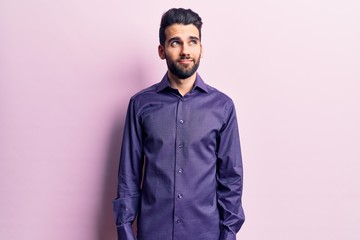 Obraz premium Young handsome man with beard wearing casual shirt smiling looking to the side and staring away thinking.