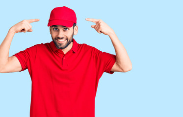 Young handsome man with beard wearing delivery uniform smiling pointing to head with both hands finger, great idea or thought, good memory