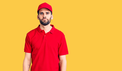 Young handsome man with beard wearing delivery uniform relaxed with serious expression on face. simple and natural looking at the camera.