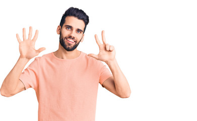 Naklejka premium Young handsome man with beard wearing casual t-shirt showing and pointing up with fingers number eight while smiling confident and happy.