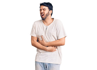 Young hispanic man wearing casual clothes with hand on stomach because nausea, painful disease feeling unwell. ache concept.