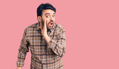 Fototapeta premium Young hispanic man wearing casual clothes hand on mouth telling secret rumor, whispering malicious talk conversation