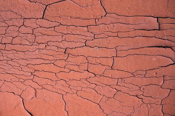 Cracked paint background. Texture with many cracks on the surface. Surface with burgundy faded paint. Close-up of a wall with many cracks. Peeling paint on the wall. Background with shabby elements. 