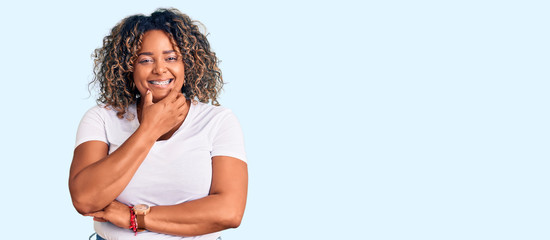 Naklejka premium Young african american plus size woman wearing casual clothes looking confident at the camera smiling with crossed arms and hand raised on chin. thinking positive.