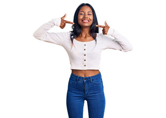 Young indian girl wearing casual clothes smiling cheerful showing and pointing with fingers teeth...
